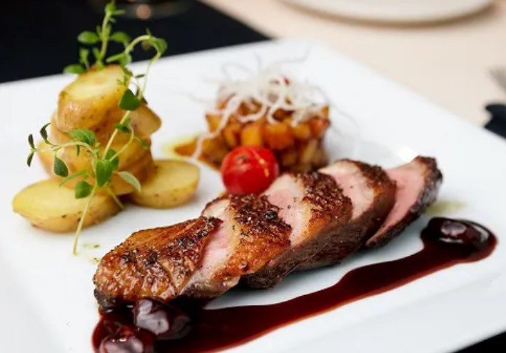 Magret de canard tranché rosé, peau croustillante, pommes grenaille, jus aux griottes